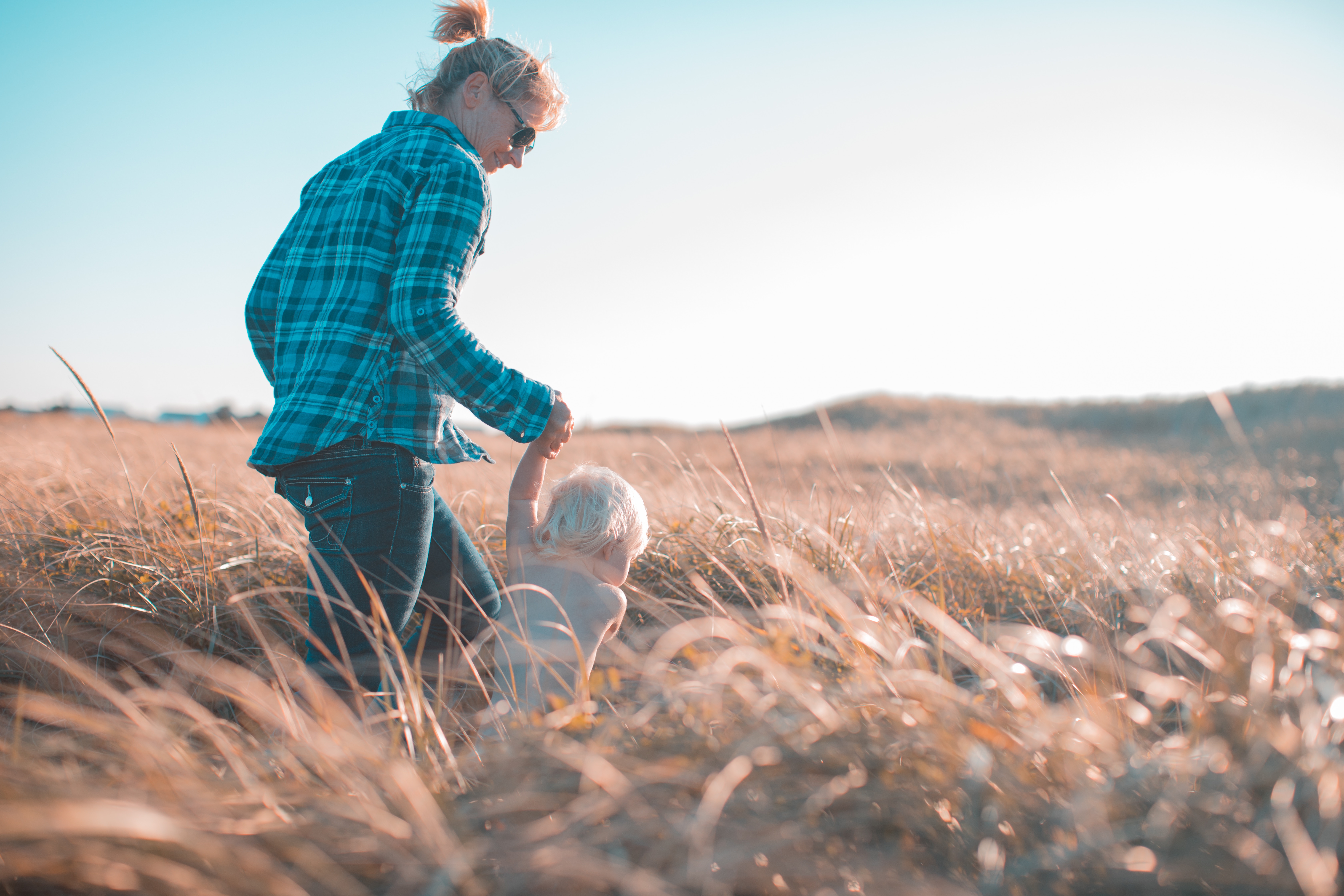Perent walking a baby through a field