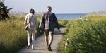 people walking a dog by the ocean